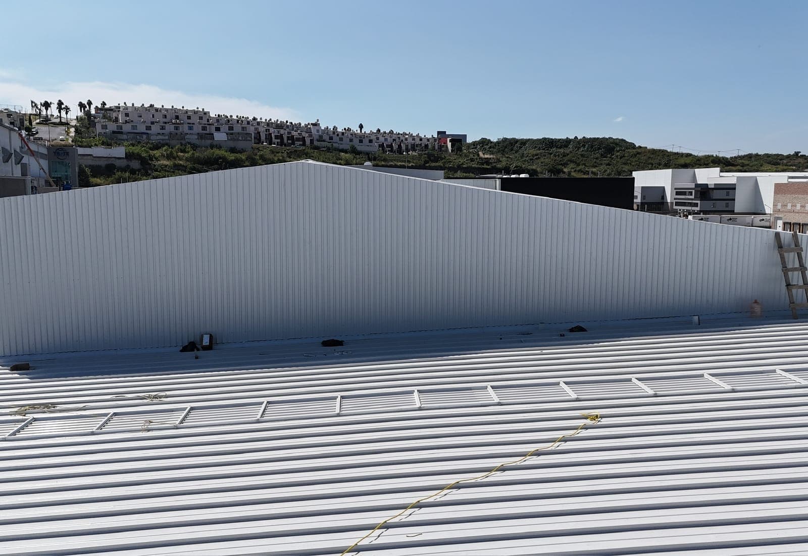 Vista aérea de la cubierta metálica de la nave industrial AXIS L3, con el cerro y la zona habitacional al fondo